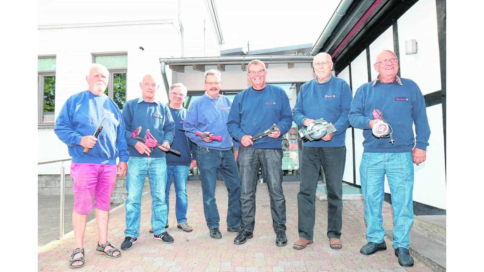 Eine Gruppe ehrenamtlicher Helfer ist mit Werkzeugen in der Hand bereit für den Einsatz im Sinne der Nachbarschaftshilfe. (Foto: tau)