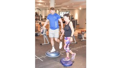 Sportlerin Renate Gießel und Trainer Jan Wiermann trainieren ihr Gleichgewicht und stehen dazu mit einem Bein auf einer wackeligen Unterlage.  (Foto: Umsorgt wohnen)