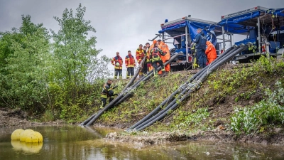 Einsatzkräfte von THW und Feuerwehr bauen an einem Ufer in Wörth zwei Hochleistungspumpen auf und verlegen Schläuche. (Foto: Lukas Hannig (THW))