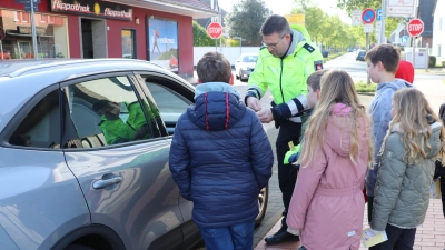 Kinder der vierten Klassen aus der Grundschule verteilen mit Polizeioberkommissar Jan Mensching gelbe Karten.  (Foto: gi)